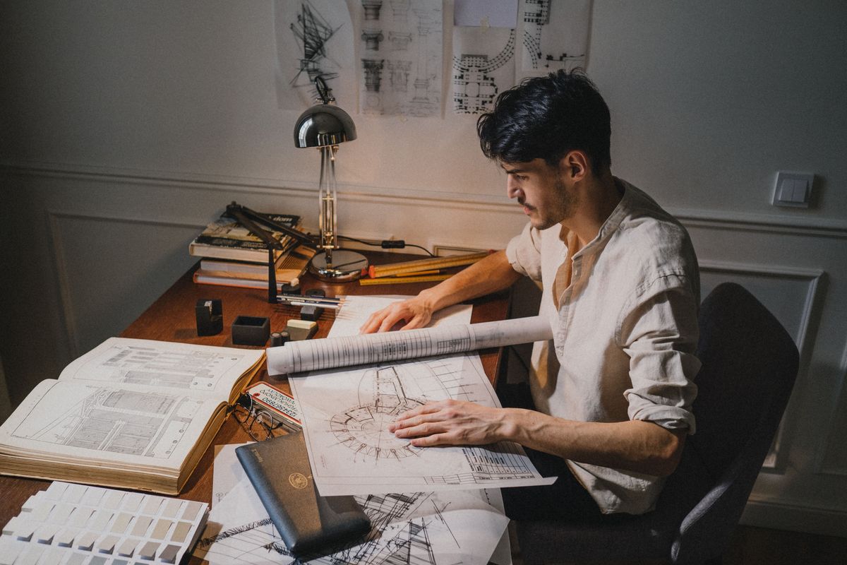 Arkitekt arbejder med tegninger ved sit tegnebord